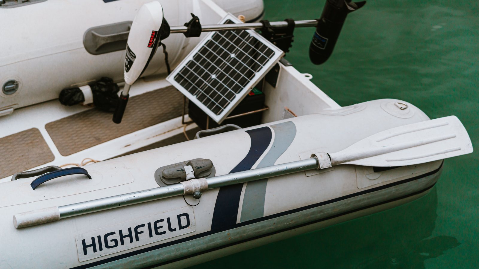 Schlauchboot mit kleinem Elektromotor und Solarmodul auf grünem Wasser